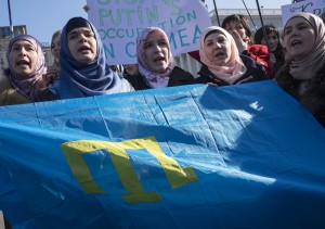 Crimean Tatars hold a national flag and shout slogans during an anti-war rally at Independence Square in Kiev